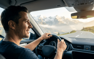 Digitale Vignette Österreich: Ein Mann fährt entspannt in einem Auto durch die österreichischen Alpen, bereit für seinen stressfreien Kurztrip dank digitaler Vignette Österreich.
