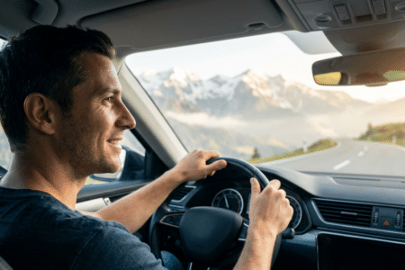 Digitale Vignette Österreich: Ein Mann fährt entspannt in einem Auto durch die österreichischen Alpen, bereit für seinen stressfreien Kurztrip dank digitaler Vignette Österreich.