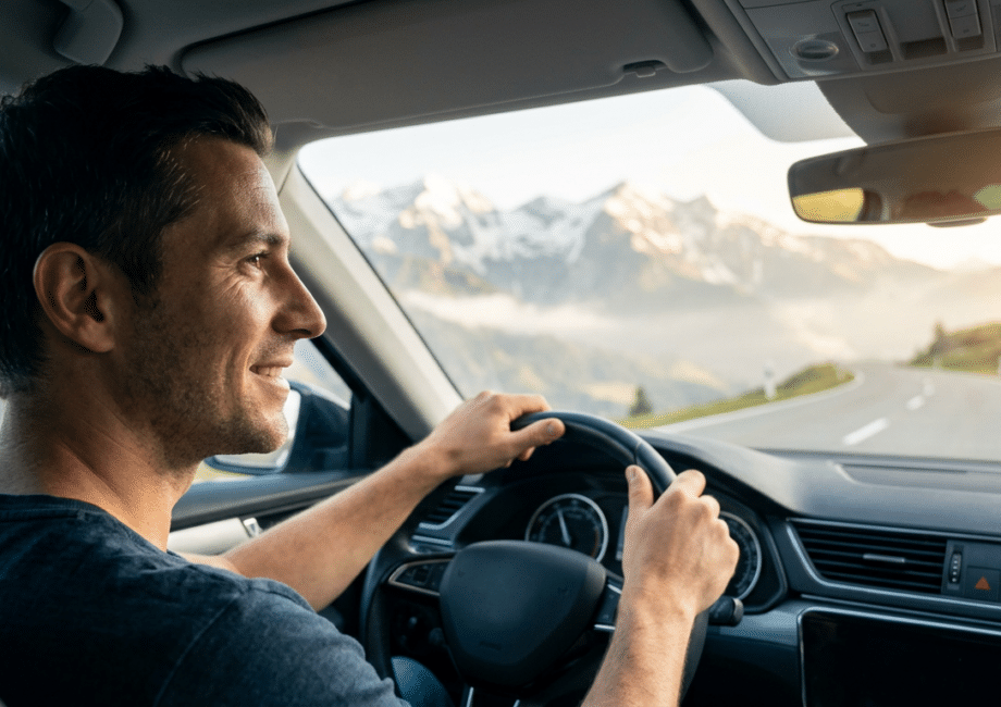 Digitale Vignette Österreich: Ein Mann fährt entspannt in einem Auto durch die österreichischen Alpen, bereit für seinen stressfreien Kurztrip dank digitaler Vignette Österreich.